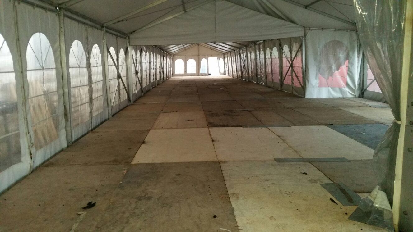 אוהל אירועים לבן ריק עם רצפת דיקטים נראה מנקודת מבט ארוכה וצרה.